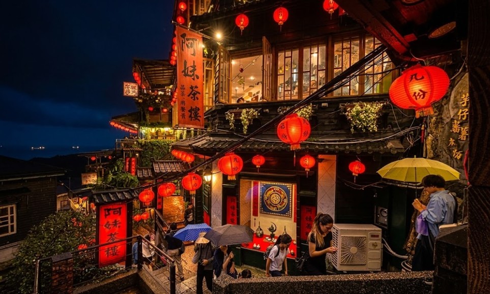 Visitors with umbrellas on a rainy night below Jiufen's lantern-lit teahouses